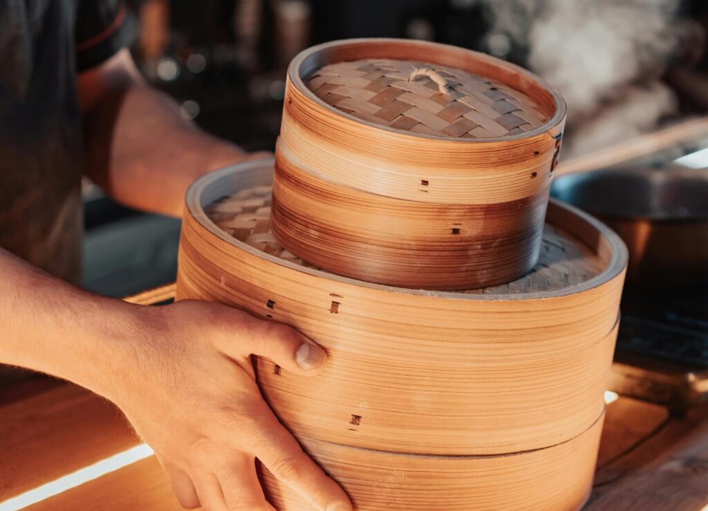 a man cooking using a bamboo steamer